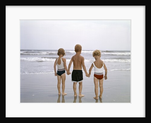 1960s Young Children In Bathing Suits Holding Hands On The Beach Looking At The Ocean Waves by Anonymous