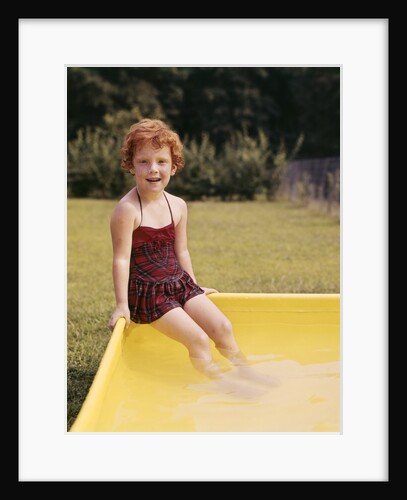 1960s Red Haired Little Girl In Plaid Bathing Suit Sitting On Yellow Plastic Backyard Swimming Pool by Anonymous