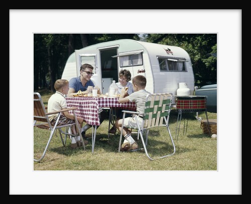 1960s Family Sitting In Lawn Chairs At Picnic Table Beside Camping Trailer by Anonymous