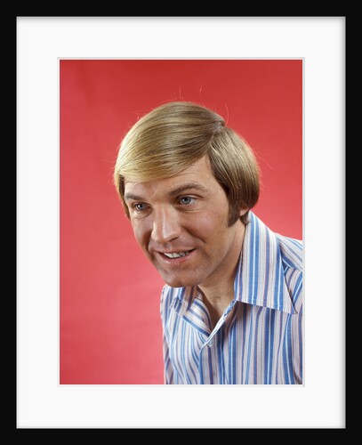 1970s Portrait Of Man With Long Hair And Blue Eyes In A Colorful Striped Casual Shirt by Anonymous