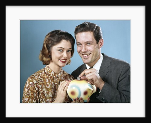 1950s 1960s Young Couple Man And Woman Put Quarter In Savings Piggy Bank by Anonymous