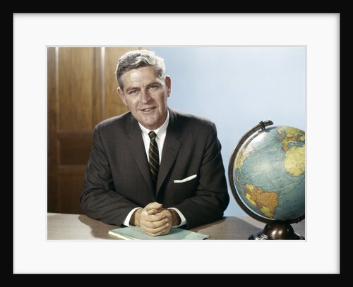 1960s Portrait Man Businessman Sitting At Desk Next To Globe Of The Earth by Anonymous
