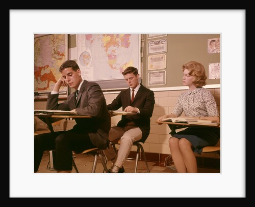 1960s 3 College High School Students Sitting Desk Chairs Reading Studying Classroom by Anonymous