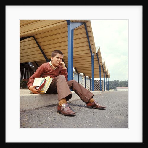 1970s Unhappy Worried School Boy Holding Books Sitting On Sidewalk Curb Outside School Building by Anonymous