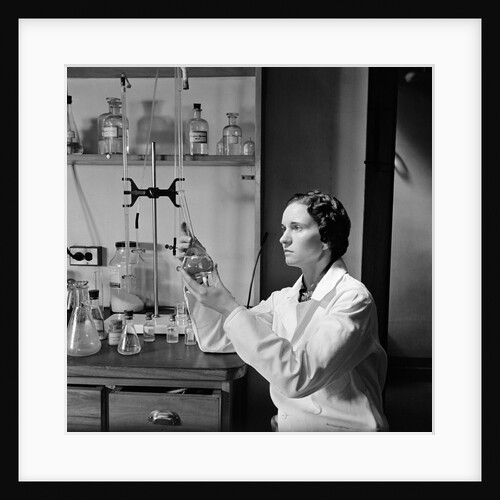 1930s 1940s Woman Scientist In Lab Coat Holding Up And Examining Beaker Of Liquid by Anonymous
