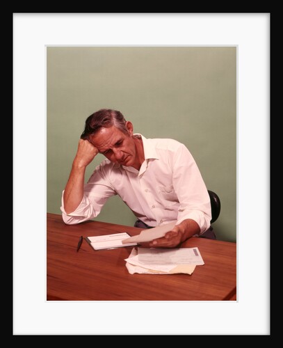 1970s Middle Age Man Sitting At Desk Worried About Bills To Pay by Anonymous