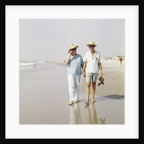 1970s Senior Couple Walking Beach Holding Hands Wearing Straw Hats by Anonymous