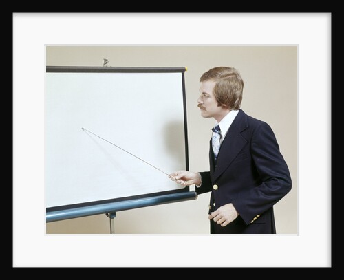 1970s Business Man Giving Presentation Pointing At Projection Screen by Anonymous