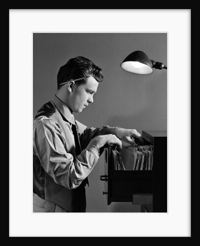 1940s Young Man Office File Clerk Putting Records Into Filing Cabinet Drawer by Anonymous