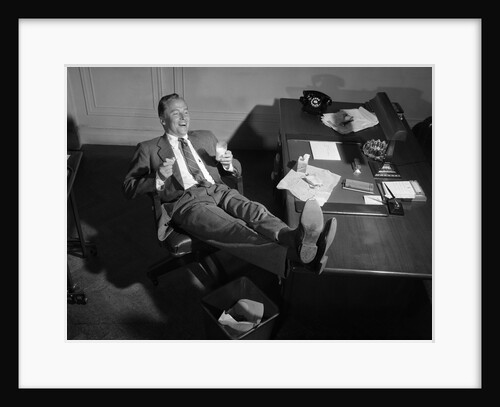 1950s Man Businessman Salesman Eating Lunch In Office With Feet Resting Up On Desk by Anonymous