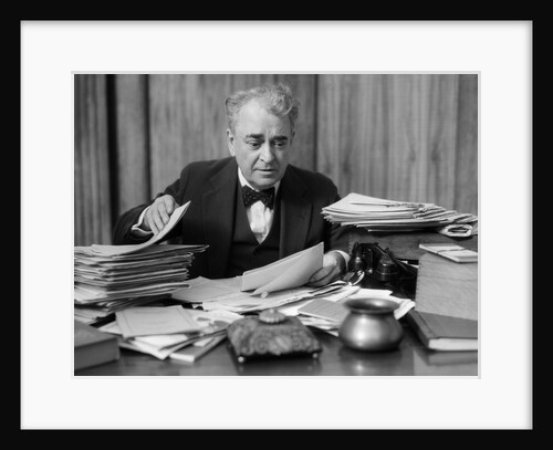 1920s 1930s Elderly Executive Man Sitting At Desk Looking Through Papers by Anonymous