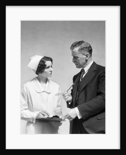 1930s Doctor In Suit And Necktie Confers With Nurse In Uniform And Cap Holding Clipboard Chart by Anonymous