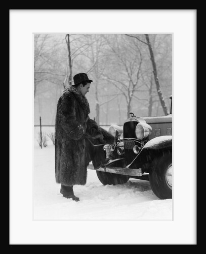 1930s Man In Hat And Raccoon Fur Coat Standing Foot On Bumper Of Chevrolet Roadster Stalled In Snow Storm by Anonymous