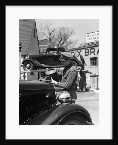1930s Service Station Attendant In Cap and Coveralls Pouring Water From Spouted Can Into Automobile Radiator by Anonymous