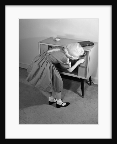 1960s Little Girl Turning On Television Set by Anonymous