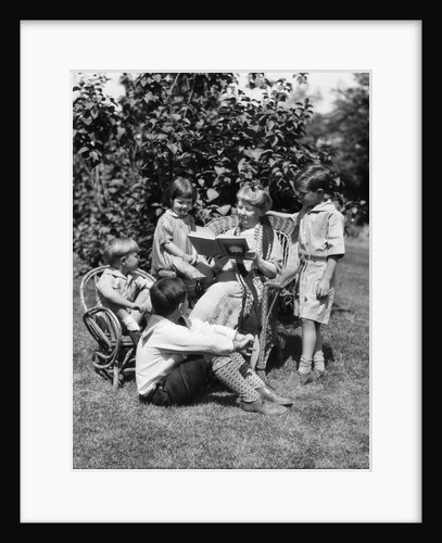 1920s Older Woman Grandmother Sitting In Wicker Chair Reading Book To Four Boys Girls Grandchildren by Anonymous
