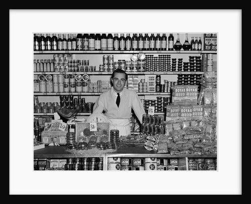 1940s Grocer Standing Behind Counter Filled With Various Food Products by Anonymous