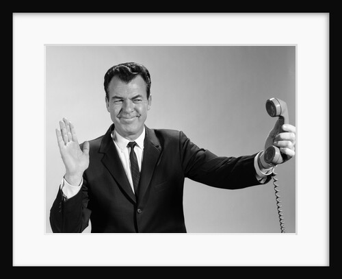 1960s Businessman Holding Telephone At Arms Length With Expression Of Disgust Or Rejection by Anonymous