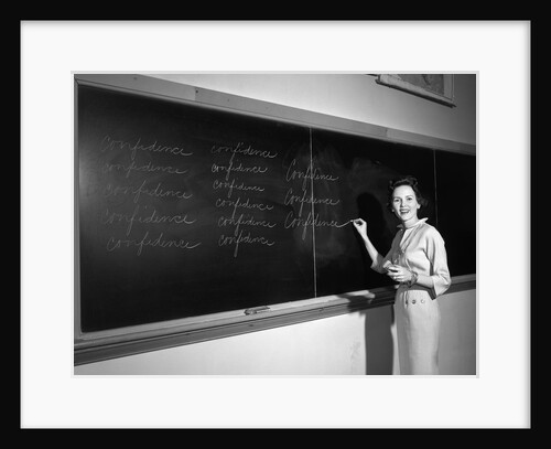 1950s Teacher In Front Of Classroom Writing Confidence On Blackboard by Anonymous