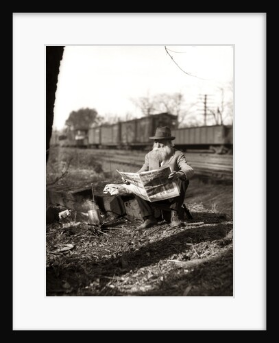 1930s Hobo Sitting By Railroad Track Reading Newspaper During Great Depression by Anonymous