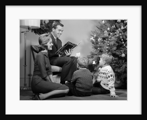 1960s Family Father Mother Two Sons Sitting By Christmas Tree In Living Room Reading A Book by Anonymous