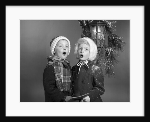 1960s Boy And Girl Singing Christmas Carol Together Under Snowy Outdoor Porch Light by Anonymous