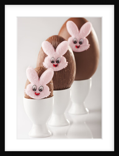 Chocolate eggs with bunny faces in egg cups by Anonymous