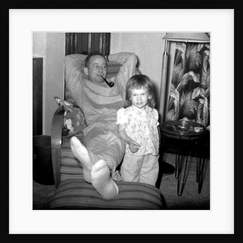 Dad relaxes and smokes his pipe with his four year old daughter, ca. 1958 by Anonymous
