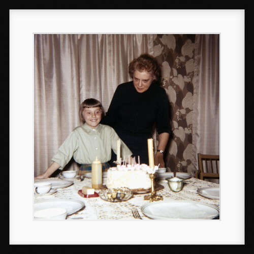 Nine year old girl is about to blow out the candles on her while her mom watches, ca. 1962 by Anonymous