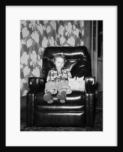 Young girl sits with her two cats in a leather chair, ca. 1960 by Anonymous