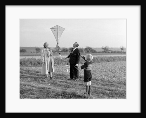 Five year old boy with mother and father fly a kite, ca. 1951 by Anonymous