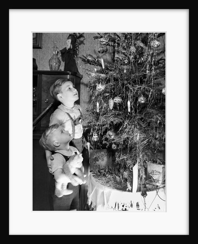 Two brothers look at a Christmas tree in their living room in Germany, ca. 1949 by Anonymous