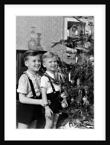 Two brothers look at a Christmas tree in their living room in Germany, ca. 1949 by Anonymous