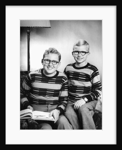 Two brothers pose with a book on their living room couch, ca. 1953 by Anonymous