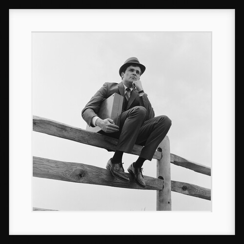 Businessman sitting on fence worried expression holding briefcase by Anonymous