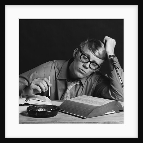 Young man studying reading books leaning on arm by Anonymous
