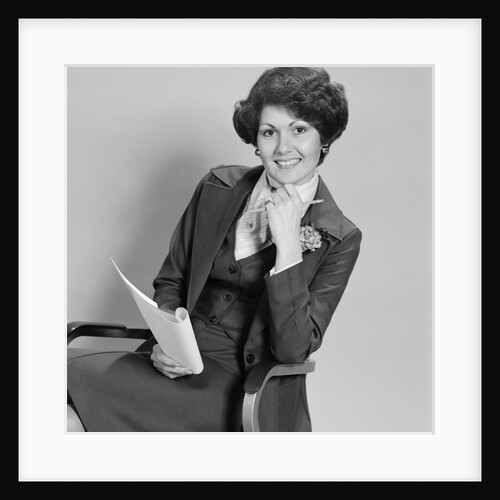 Smiling woman sitting in office chair holding papers by Anonymous