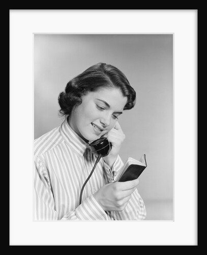 Young woman talking on telephone reading address from little black book by Anonymous