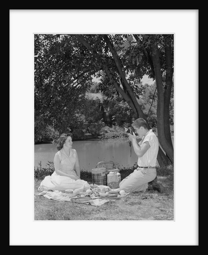 Teenage couple picnic boy taking photograph of girl outdoors by Anonymous