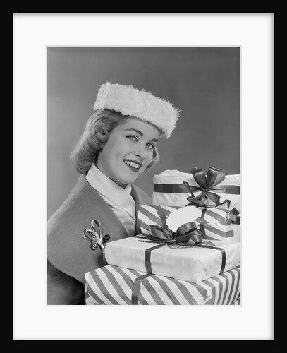 Smiling woman in fur hat holding wrapped christmas presents by Anonymous