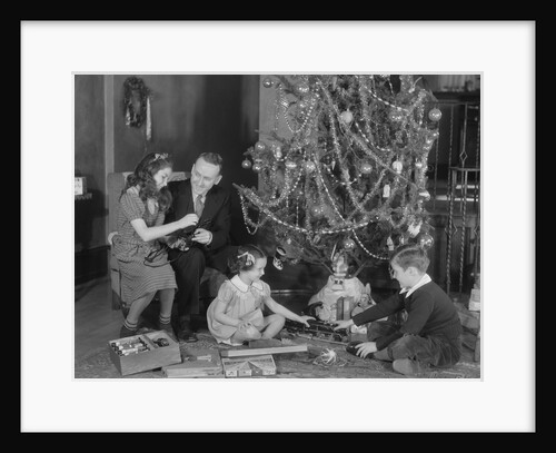 Family christmas photo father two daughters and son with presents and tree by Anonymous