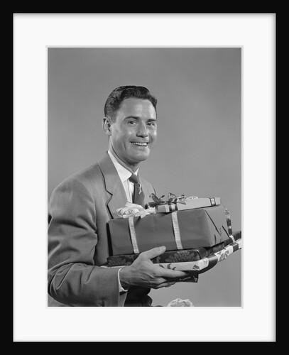 Smiling man holding wrapped christmas presents by Anonymous