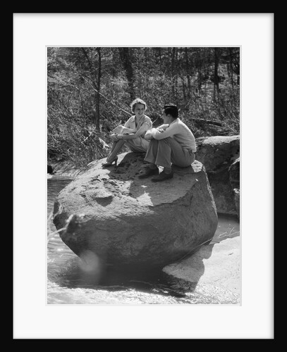 Couple man woman sitting on large rock in stream hugging knees smiling happy romance by Anonymous