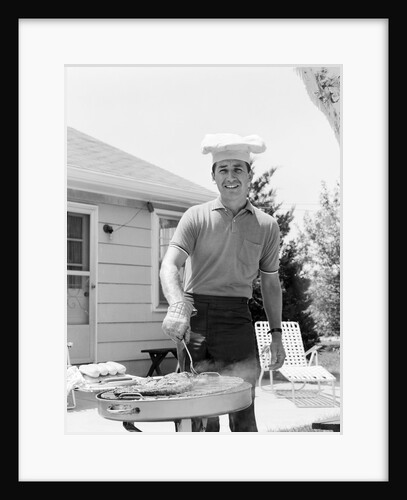 Smiling man outdoors in backyard patio wearing chef hat cooking steaks hot dogs on grill by Anonymous