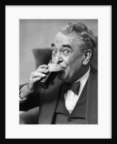 Smiling eyes of senior man drinking beer from glass by Anonymous