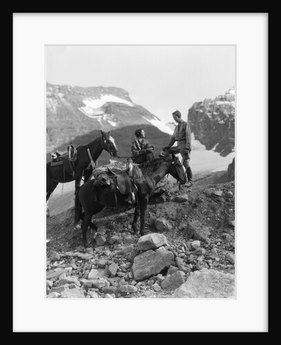 Couple man woman wearing riding gear jodhpurs boots spurs sitting standing on large rock by two horses by Anonymous