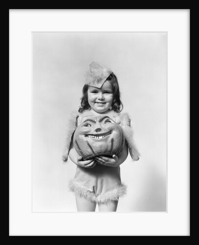Happy smiling little girl in costume holding a papier-mache pumpkin head by Anonymous