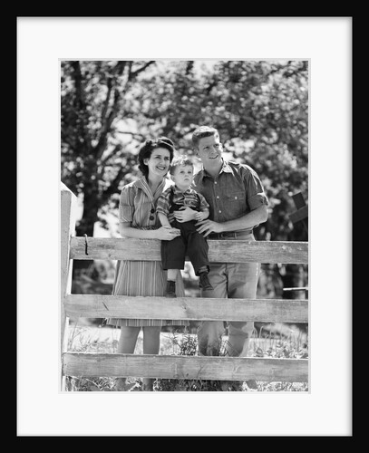 Smiling happy family mother father toddler boy portrait by farm fence by Anonymous