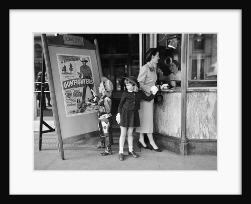 Mother and 2 children buying tickets to movie matinee boy wearing cowboy costume by Anonymous