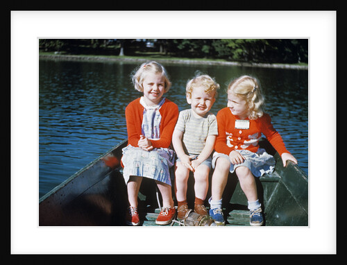 Boy and two girls in red sweaters sitting in back of rowboat by Anonymous